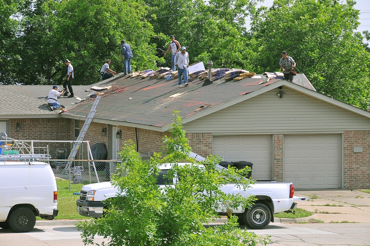 A roofing crew replacing the shingles on a house
